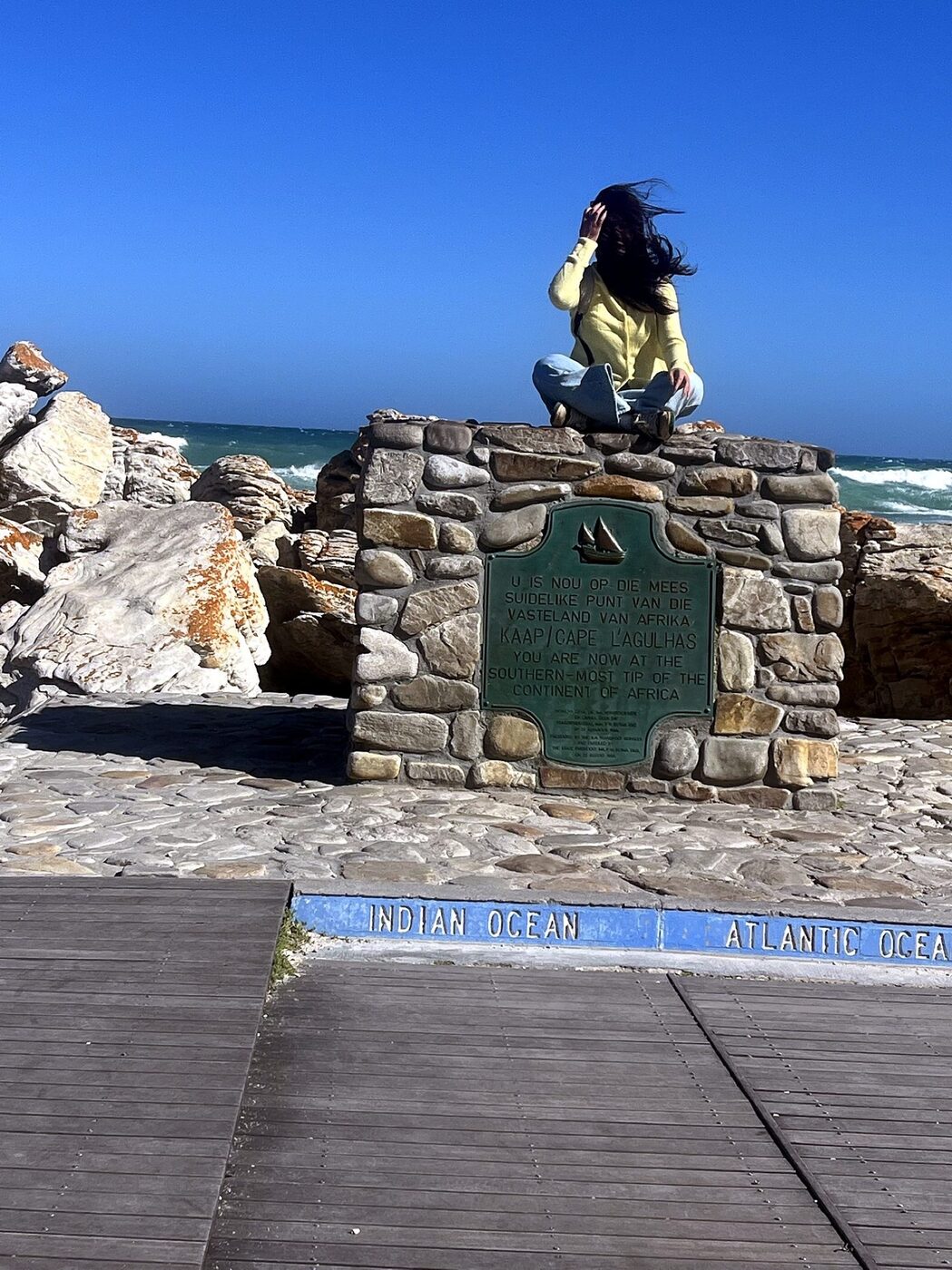 Guest at the Cape Agulhas marker where the Indian and Atlantic Oceans meet