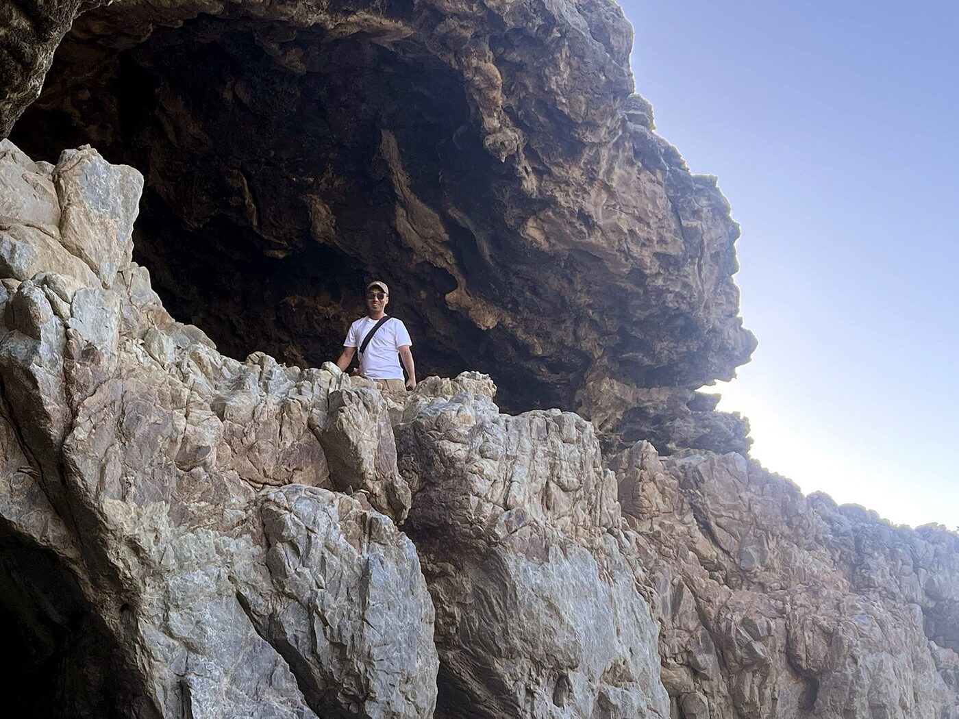 Guest standing under the rock overhang at Klipgat Caves